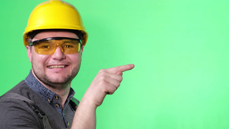 Construction worker wearing a yellow helmet he poses on a background of chromakey