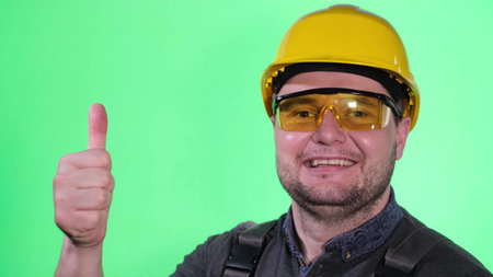 Portrait of a male builder on a background of a chromakey in the studio wearing a yellow helmet