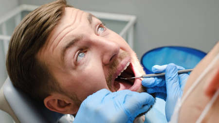 The concept of modern dentistry and healthcare. A young man is treating his teeth.の写真素材