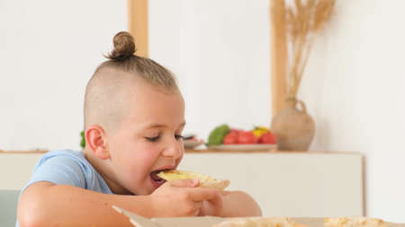 Happy family eating delicious pizza sitting in the kitchen at the table. The concept of culinaryの写真素材