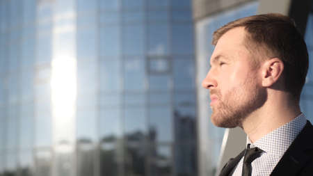 The young boss raises his hand and looks at the sky. Businessman looking at something on the horizonの写真素材