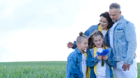 Happy family walks on a green field, they are dressed in denim clothes.の写真素材
