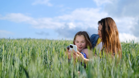 Happy family and children are resting. Mother and daughter walk in a green field of young wheat.