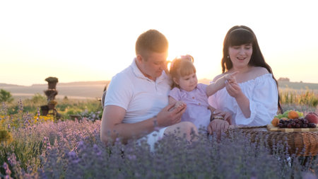 Young happy family on a picnic in a lavender field. Outdoor weekend at sunset.の写真素材