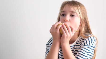 a little girl eats a sweet pear. Healthy fruit snacks at home, child eating fruit.の写真素材