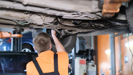 An American auto mechanic inspects a car while working in an auto repair shop. Car repairの写真素材