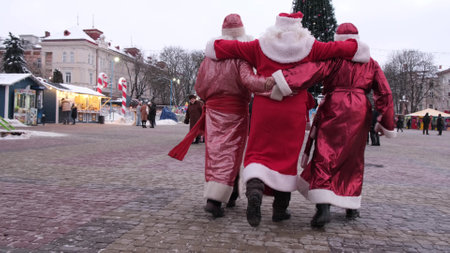 three Santa Clauses walk hugging, drunken Santa Claus on the streets of the cityの写真素材
