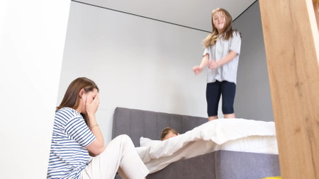 Restless boy and girl jump on the bed in the bedroom.の写真素材