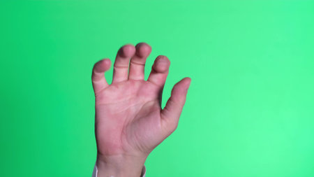 Male hand clenched on a green background of the color key screen. Interface concept.の写真素材