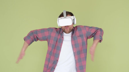 Man with virtual reality glasses dancing in the studio on a yellow-green background. Funny dance