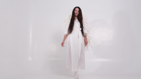 Beautiful woman in the image of an angel with long straight hair circling on a white backgroundの写真素材