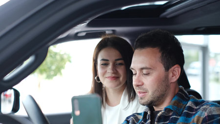 Happy and smiling husband and wife taking selfie in new car