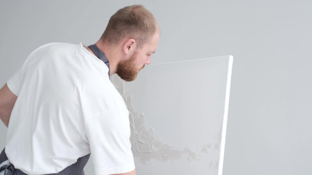 A creative artist paints a creative picture on a canvas. The process of painting in the workshop.の写真素材