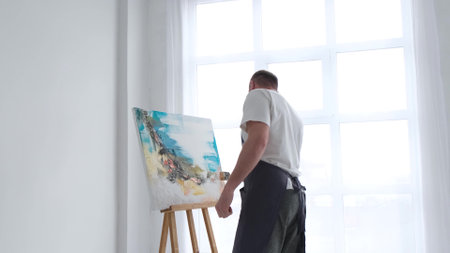 An artist paints a piece of art on a canvas with color oil painting at home. An artist works and creatively works.の写真素材