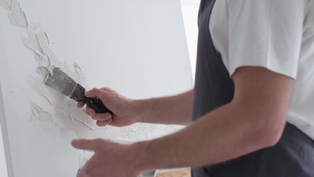 A male artist works on painting a picture in a creative studio, creates an abstract painting. Bright creative studio.の写真素材
