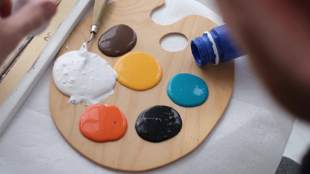 The artist prepares the paints for writing the nartina. An artist works on an abstract oil painting in a workshop.の写真素材