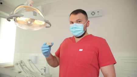 Professional dentist in red uniform in dental officeの写真素材