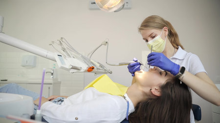 Beautiful woman patient having dental treatment at dentists office. Women dentist.
