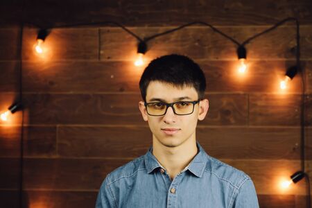 young businessman wearing glasses, looking at the camera on a wooden backgroundの写真素材