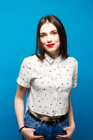 Young pretty woman smilig and standing confident blue backgroundの写真素材