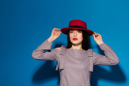 Fashion Brunette Lady in red hat and red lips on blue background.の写真素材