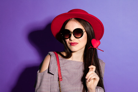 Lovely model in fashionable red Hat and a red Clutch on blue background.の写真素材