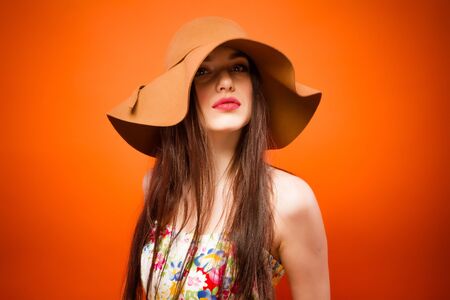 Beautiful smiling woman. Over orange background. Fashion studio portraitの写真素材