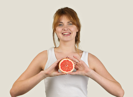 sporty woman over gray background holding glass of grapefruit juice.の写真素材