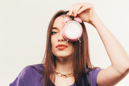 The young business woman in glasses with alarm clock.