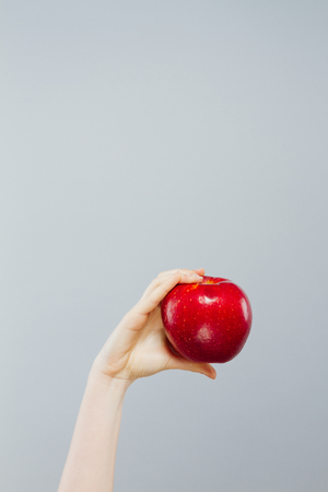 Woman on diet with an apple in the hand against gray backgroundの写真素材