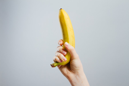 Hand with painted nails clutching a bananaの写真素材