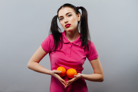 Lovely girl with black hair holding orangeの写真素材