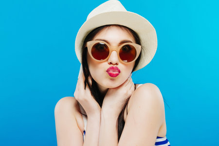 Cheerful beautiful girl in hat and sun glasses. Smiling widely, looking and pointing aside. Summer...