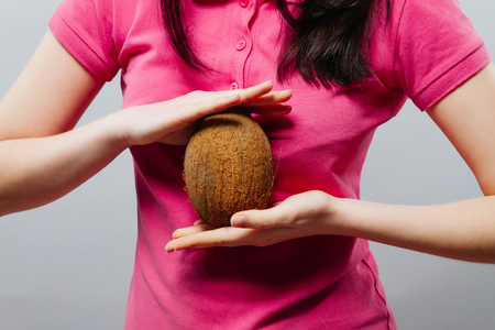 Girl is holding a coconut over grey background,の写真素材