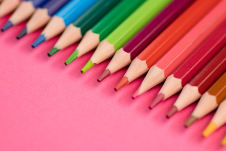 Many Different Colored Pencils Lying on Pink Background in a Waveの写真素材