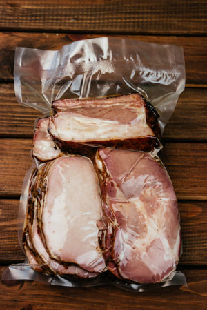 Traditional ham. Smoked, boneless pork ham with herbs and spices, wrapped in string. Wood background,の写真素材