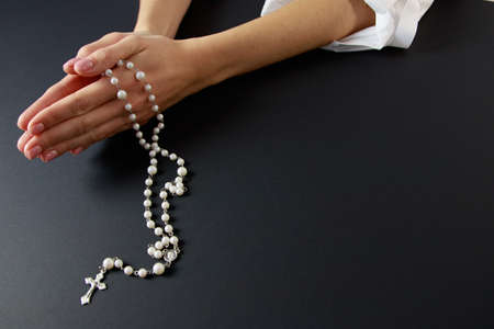 Woman (only closeup of hands to be seen) with rosary sending a prayer to God, The girl prays for peace and for overcoming the pandemicの写真素材