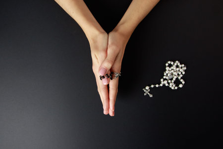 Woman (only closeup of hands to be seen) with rosary sending a prayer to God, The girl prays for...
