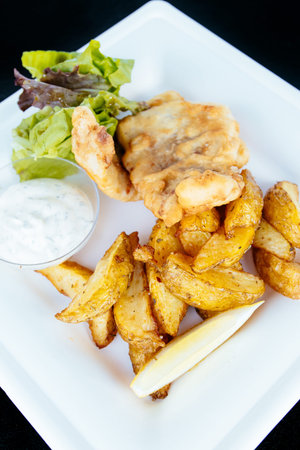 Fried fish with french fries on a plate with garlic sauce. High quality photo