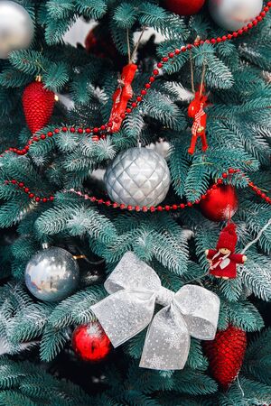 Decorated Christmas tree closeup. Red and golden balls and illuminated garland with flashlights. New Year baubles macro photo with bokeh. Winter holiday light decoratioの写真素材