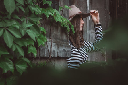 Beautiful woman in a striped shirt holding her hat.