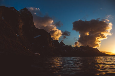 Sunset over the mountains by the sea. Silhouette of the mountains. Beautiful clouds