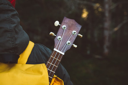 Details of the guitar from the backpack. Shoot from the back Traveler man is standing on a trail in...