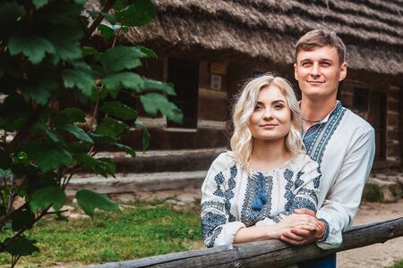 Amazing wedding couple holding hands and hugging against a background of a wooden houseの写真素材