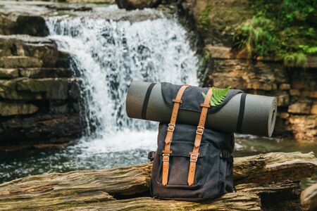 Hipster hiker tourist backpack on the background of the river and the waterfall , traveler relax holiday concept, travel adventure.の写真素材