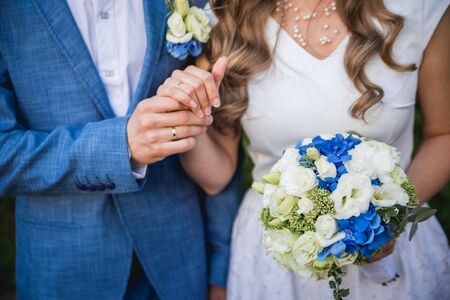 Wedding couple holding hands with a bouquet of flowers and wedding rings. Wedding detailsの写真素材