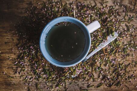 Cup with fragrant, flowered black tea on a wooden background. Breakfast, health, herbal therapy, healthy food. Concept and composition. Top viewの写真素材