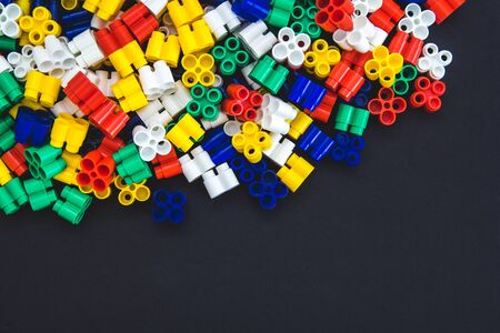 Multicolored plastic blocks on a black background with a place for text. Parts of the bright little spare parts for toys. Top view.の写真素材