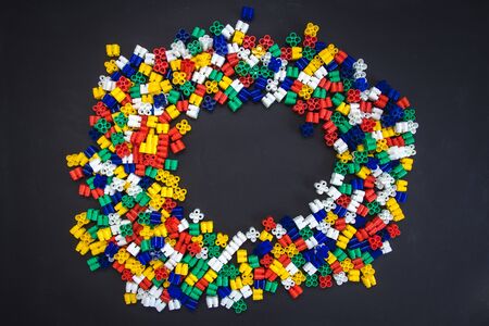 Multicolored plastic blocks on a black background with a place for text. Parts of the bright little spare parts for toys. Top view.の写真素材