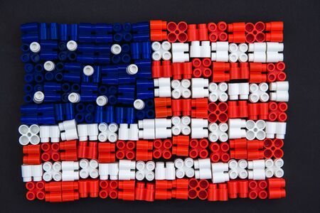 Colorful plastic bricks which form the US flag on black paper background. Parts of bright small spare parts for toys. Top viewの写真素材